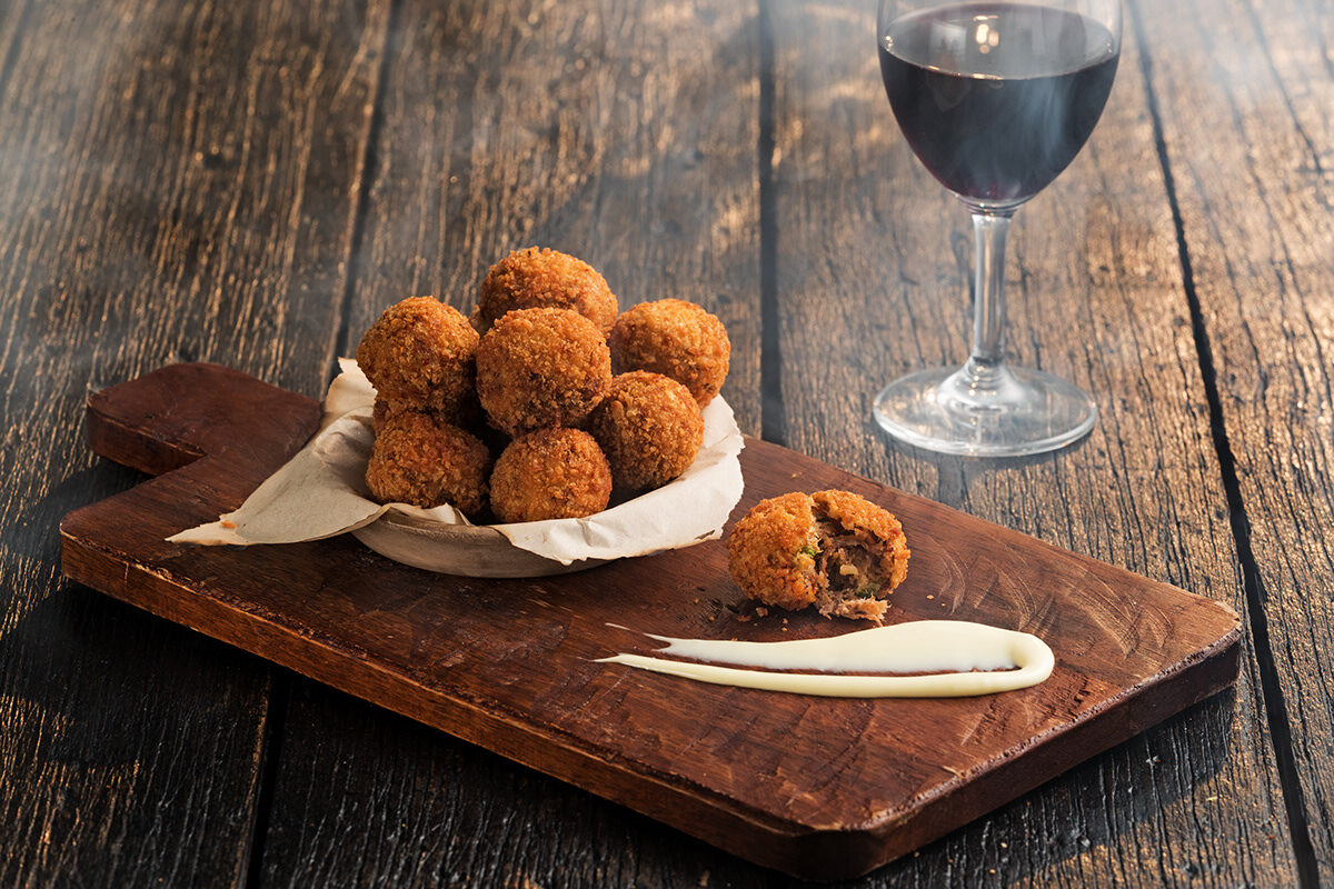 Omni Season of Smoke — smoked arancini on a cutting board with red wine